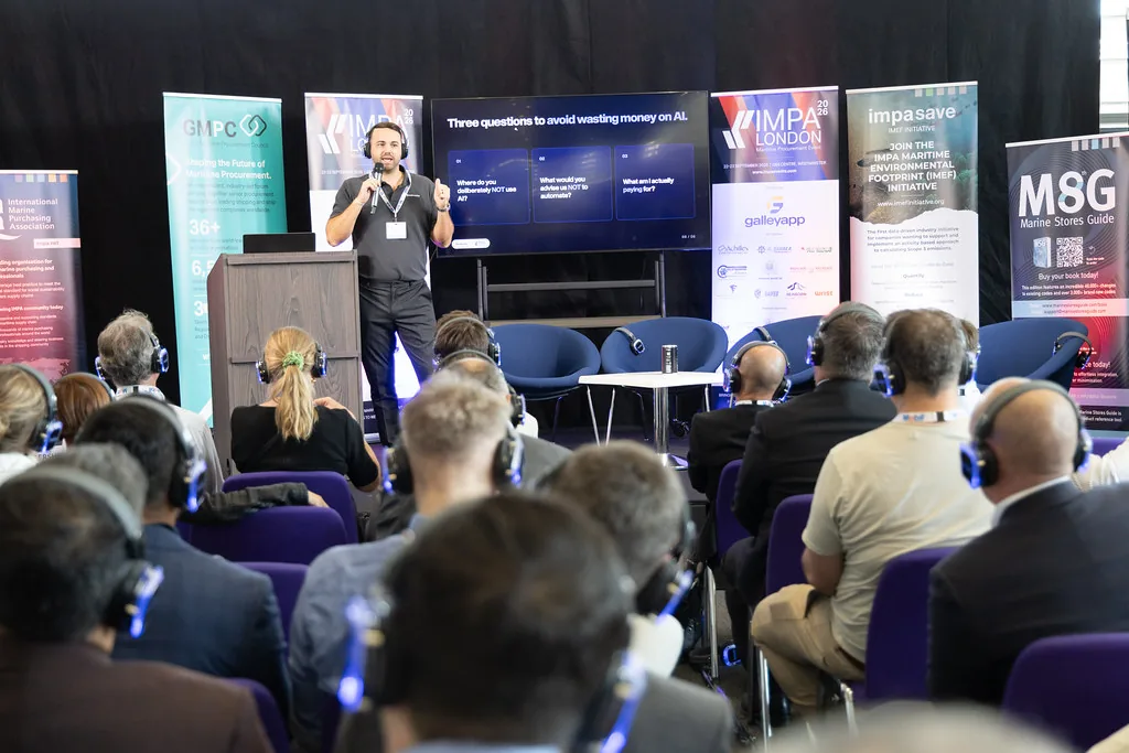 Will Rush presenting on the IMPA London 2026 conference stage to a seated audience, with the closing slide, Three questions to avoid wasting money on AI, on the screen behind him